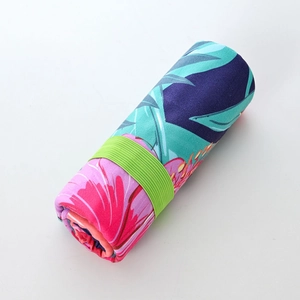 Rolled quick-dry floral beach towel with green elastic band for compact storage