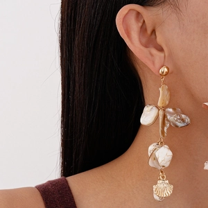 Close-up of gold shell drop earrings with irregular beads on model for vacation style