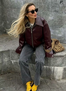 Street style shot of a burgundy faux leather biker jacket with a wide lapel collar