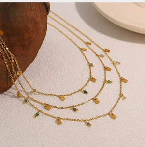 Detail of bohemian gold layered necklace with geometric pendants and colorful beads