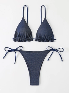 Détail d'un bikini bleu foncé à volants avec une finition métallique dorée scintillante