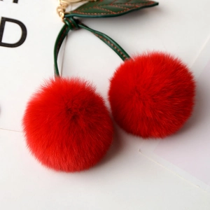 Detail of red faux rabbit fur cherry keychain with green leather leaves and gold clasp
