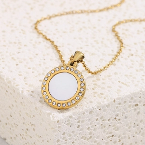 Macro shot of 18K gold plated necklace featuring a round shell pendant with inlaid crystals