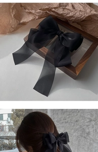 Detail of elegant black tulle bow hair clip showing fabric texture and hair styling view