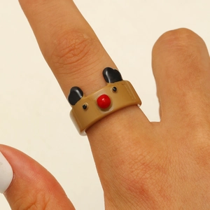 Close-up of a cute brown reindeer resin ring with a red nose and black ears on a finger