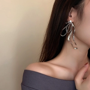 Détail de boucles d'oreilles nœud argenté avec strass brillants portées par un mannequin