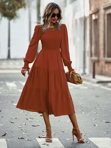 Détail d'une robe midi rouille à manches longues avec buste froncé et jupe à volants