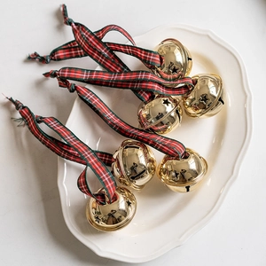 Golden Christmas bells with red and green plaid ribbons on a ceramic tray