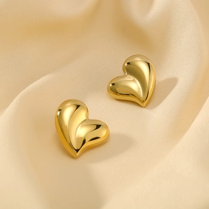 Detail of 18K gold plated heart stud earrings on elegant champagne satin fabric