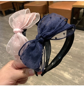 Close-up of black lace headbands with large pink and navy blue polka dot mesh bows