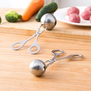Dual stainless steel meatball makers on wooden board with fresh kitchen ingredients