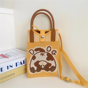 Close-up of yellow knitted crossbody bag with a cute cartoon bear pattern and brown handle