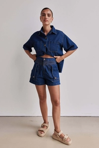 Detail eines dunkelblauen Jeans-Sets aus Baumwolle mit Kurzarmhemd und hoher Taille