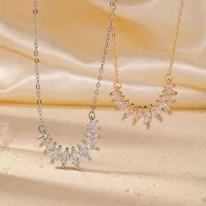 Elegant gold and silver teardrop zircon necklaces on soft silk and stone background