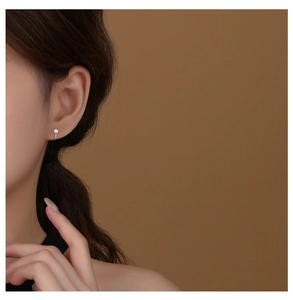 Close-up of minimalist s925 silver curved stud earring with a round cubic zirconia