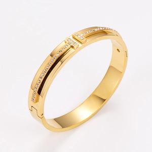 Detailed view of a gold-toned H-shaped bangle featuring shimmering pavé diamond accents