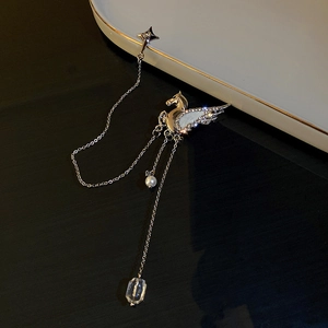 Macro detail of silver Pegasus brooch with star charms, pearls and crystal tassels