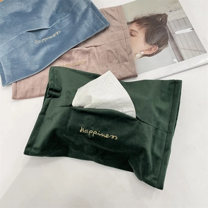 Detail of velvet tissue bags with Happiness embroidery in blue, pink, and green