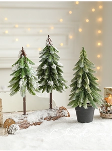 Miniature snow-flocked Christmas trees with natural wood bases for festive table decor