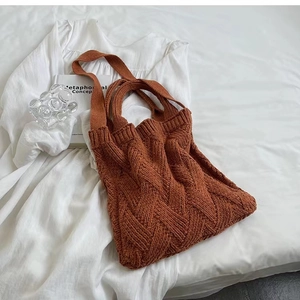 Detail view of brown cable-knit texture on a spacious commute tote bag in a cozy setting
