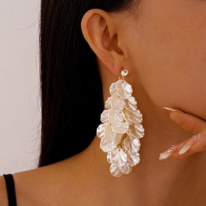 Close-up of elegant long tassel earrings with white acrylic petals and sparkling zircon studs