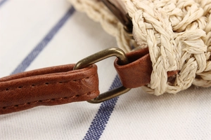 Detail of paper rope woven beach bag with brown faux leather strap and bronze buckle
