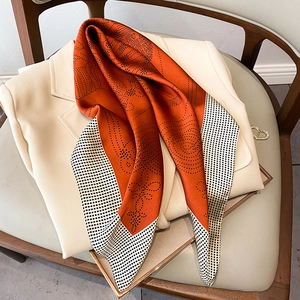 Elegant orange silk scarf with black polka dots and vintage patterns on a beige blazer