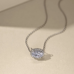 Détail macro d'un collier en argent avec pendentif zircon ovale et sertissage halo brillant