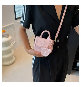 Detail view of mini pink PU leather handbag with cute white bear charm and shoulder strap