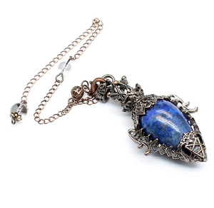 Close-up of vintage bronze teardrop pendant with deep blue crystal and ornate filigree