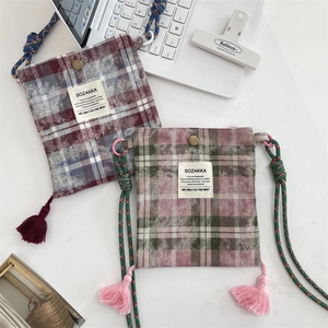 Detail of plaid fabric crossbody bags with fringe tassels and woven rope straps