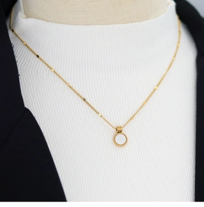 Detail of 18K gold-plated titanium necklace with white shell pendant on a model shirt