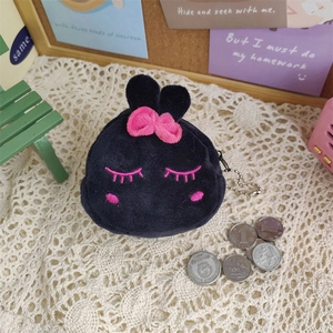 Detailed close-up of a black plush coin purse with a pink bow and cute embroidery