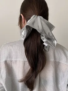 Detail of a large metallic silver hair scrunchie with shiny coating on high ponytail