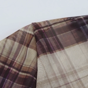 Close-up detail of sheer mesh fabric with vintage brown plaid pattern and fine stitching