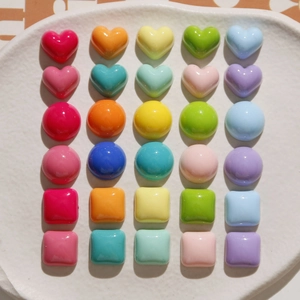 Colorful resin heart, round, and square charms for DIY crafts displayed on a ceramic plate