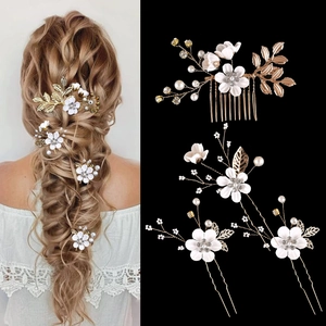 Detailed bridal hair set featuring white flowers, gold leaves, and faux pearls on a comb
