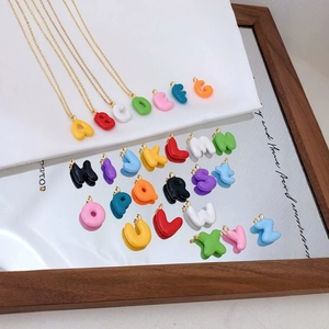 Schicke Buchstabenanhänger an Goldketten, präsentiert auf einer Spiegelfläche