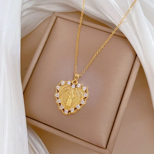 Detail of gold heart pendant featuring a Saint Benedict coin and clear zircon stones