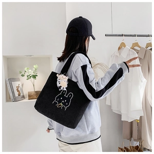 Black corduroy tote bag with white rabbit embroidery shown on model in home setting