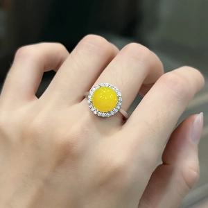 Detail view of a silver ring featuring a round yellow chalcedony stone and diamond halo