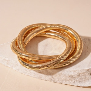 Three-layer golden spiral cuff bracelet with textured metallic finish on stone base