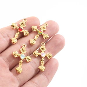 Detail of four golden cross pendants with colorful heart-shaped gemstones held in hand