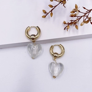 Détails de boucles d'oreilles créoles dorées avec pendentifs cœur translucides