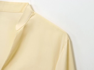 Close-up of light yellow poplin shirt featuring a stand collar and woven fabric detail