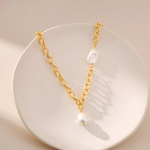 Close-up of elegant French irregular pearls on 18K gold plated chain on ceramic tray