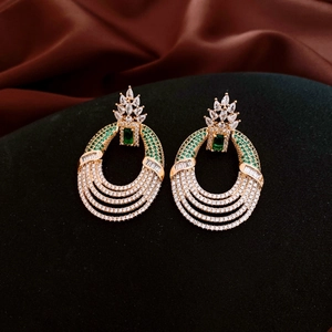 Detail of vintage gold-tone earrings with emerald green square stones and zircon stones