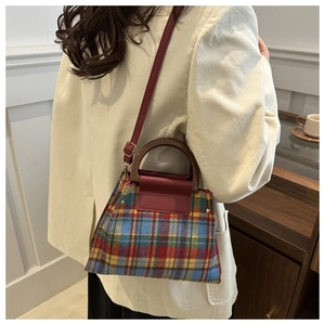 Detail showing vintage plaid handbag with a wooden handle and red leather strap