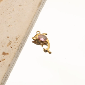 Close-up of 18K gold starfish pendant with a pink gemstone on a reflective surface