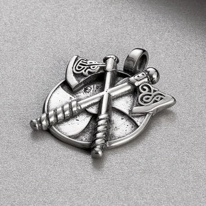 Macro detail of silver vintage Viking shield pendant with crossed axes on textured background